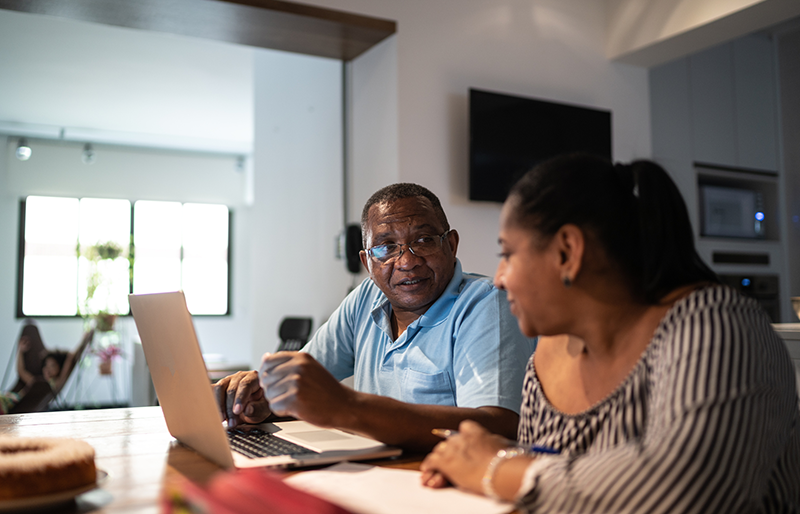A retired couple works on a laptop.